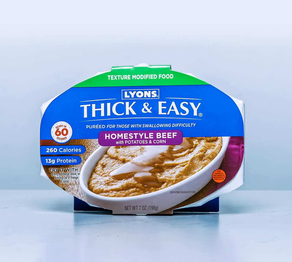 Packaging of Lyons Thick & Easy Homestyle Beef with Potatoes & Corn on a light blue background.