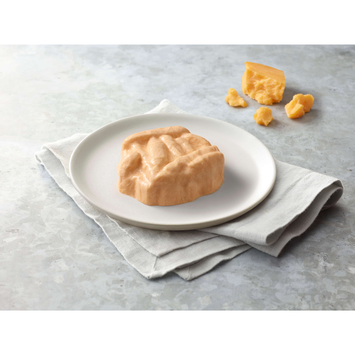 Mac and cheese on a white plate with a napkin on a gray surface.