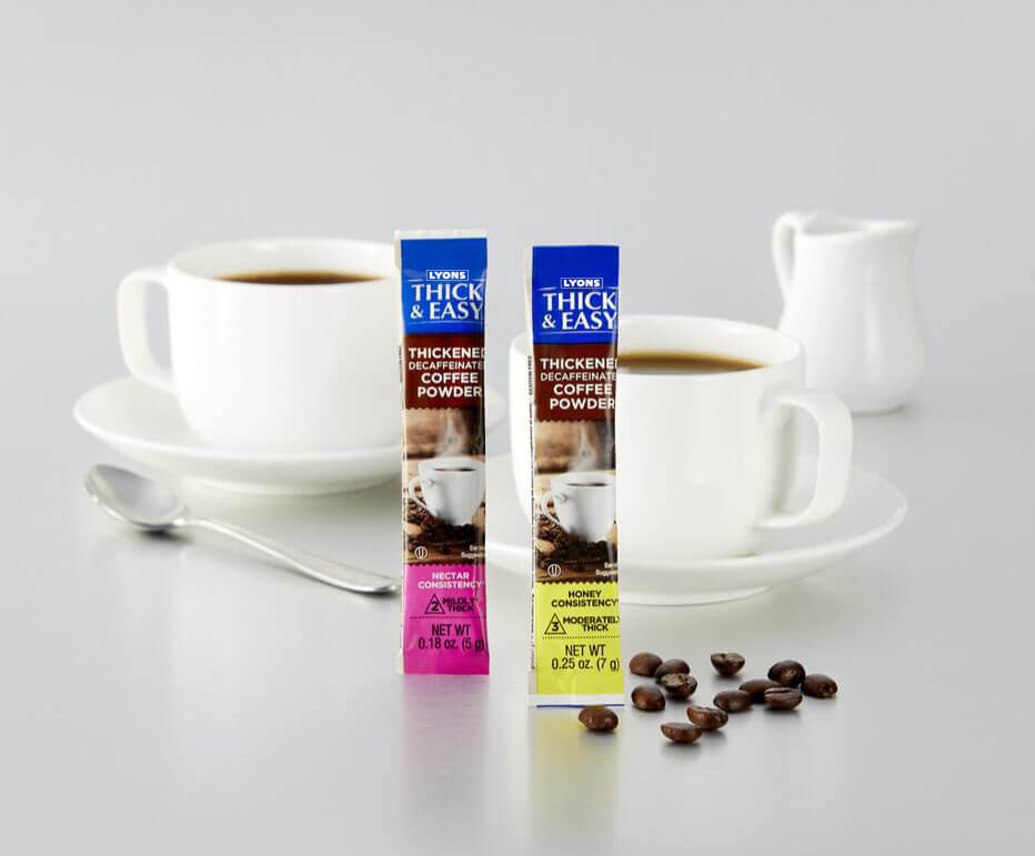 Two packets of Thick & Easy thickening coffee powder with a cup of coffee and coffee beans on a white background.