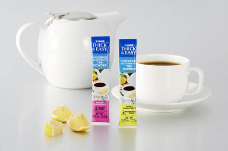Two boxes of thick and easy thickening tea powder with a cup of tea and lemons on a white background.