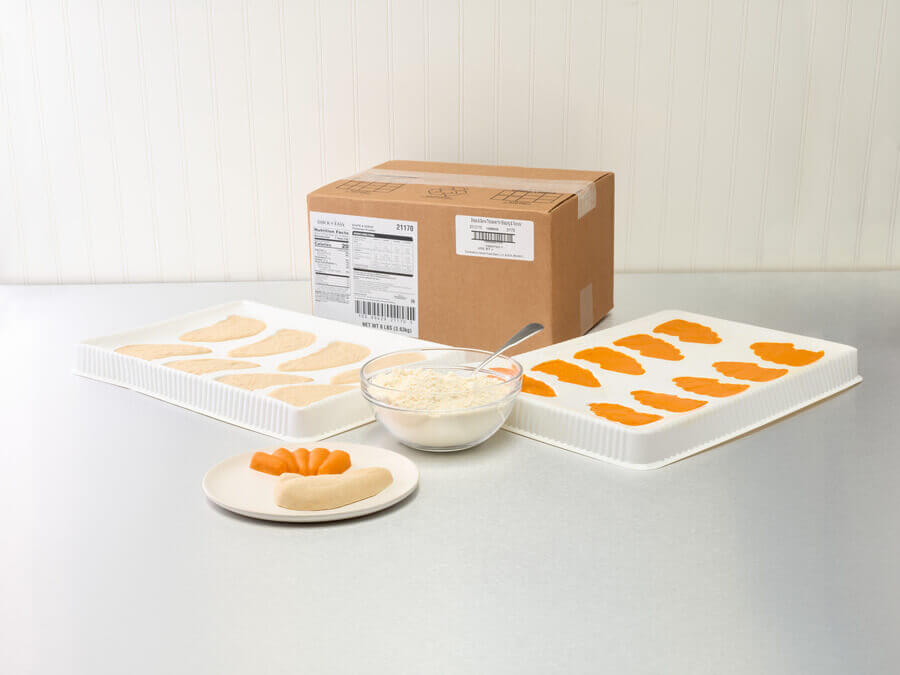 Packaged food items including a box, trays with orange slices, and a bowl on a light surface.
