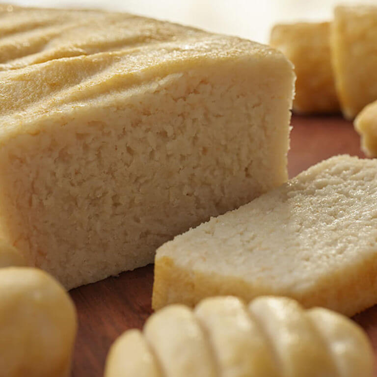 Close-up of a loaf of bread with slices cut from it on a wooden surface.