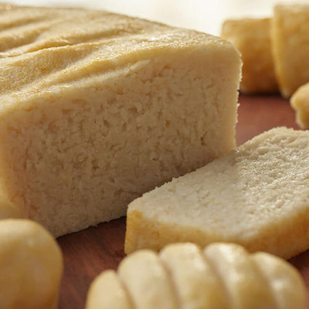 Close-up of a loaf of bread with slices cut from it on a wooden surface.