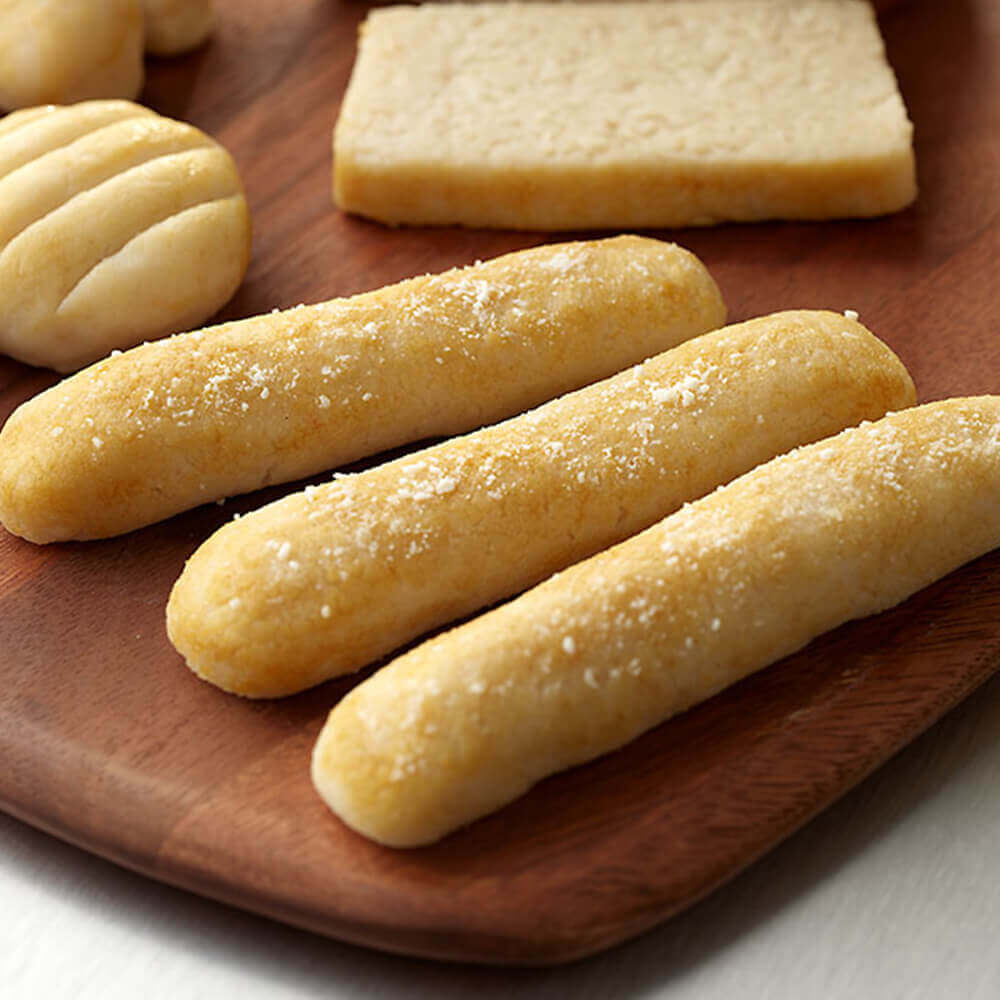 Breadsticks on a wooden plate with a soft focus background.