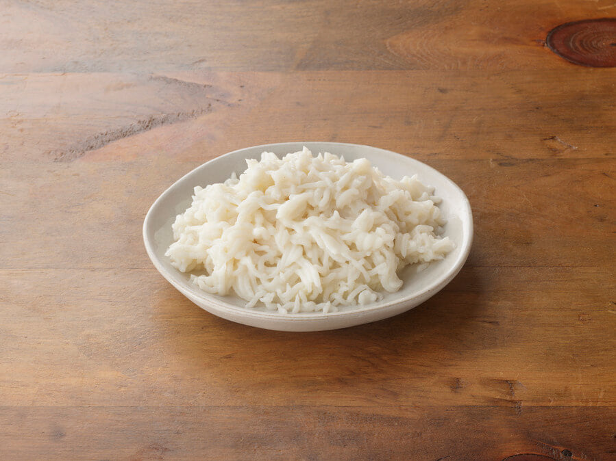 White plate with rice on a wooden surface.
