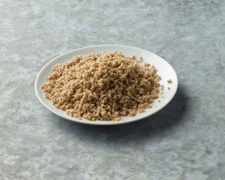 White plate with brown quinoa on a gray surface.