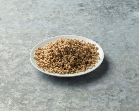 White plate with brown quinoa on a gray surface.