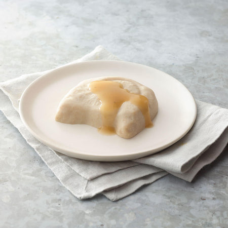 Chicken with a custard-like topping on a white plate with a light gray background.
