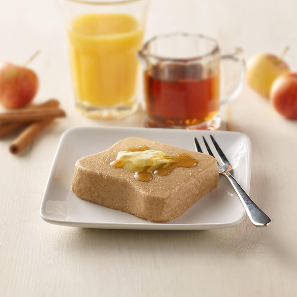 Toast with butter and honey on a plate with a glass of orange juice and mug of tea in the background.