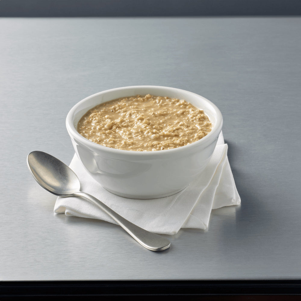 White bowl of oatmeal with a spoon on a gray surface.