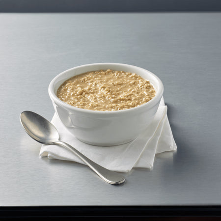 White bowl of oatmeal with a spoon on a gray surface.