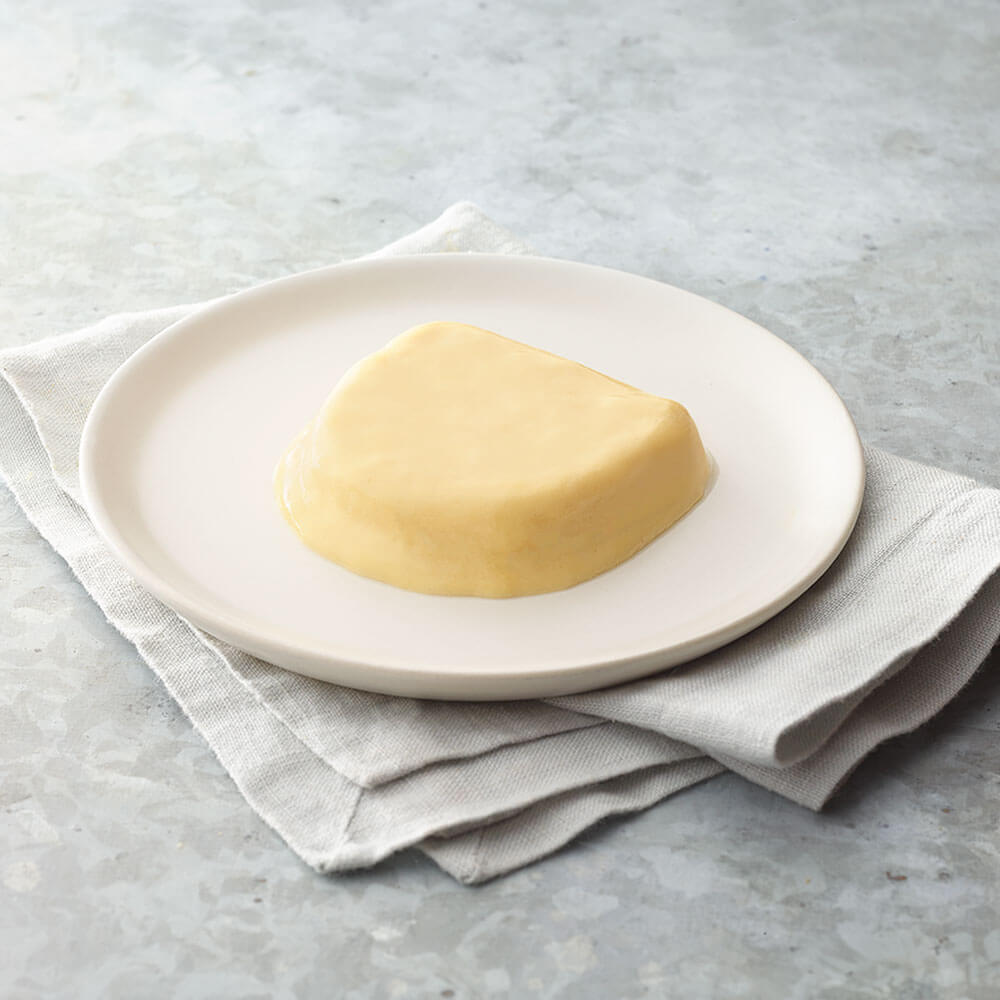 Block of omelet on a white plate with a light gray background.