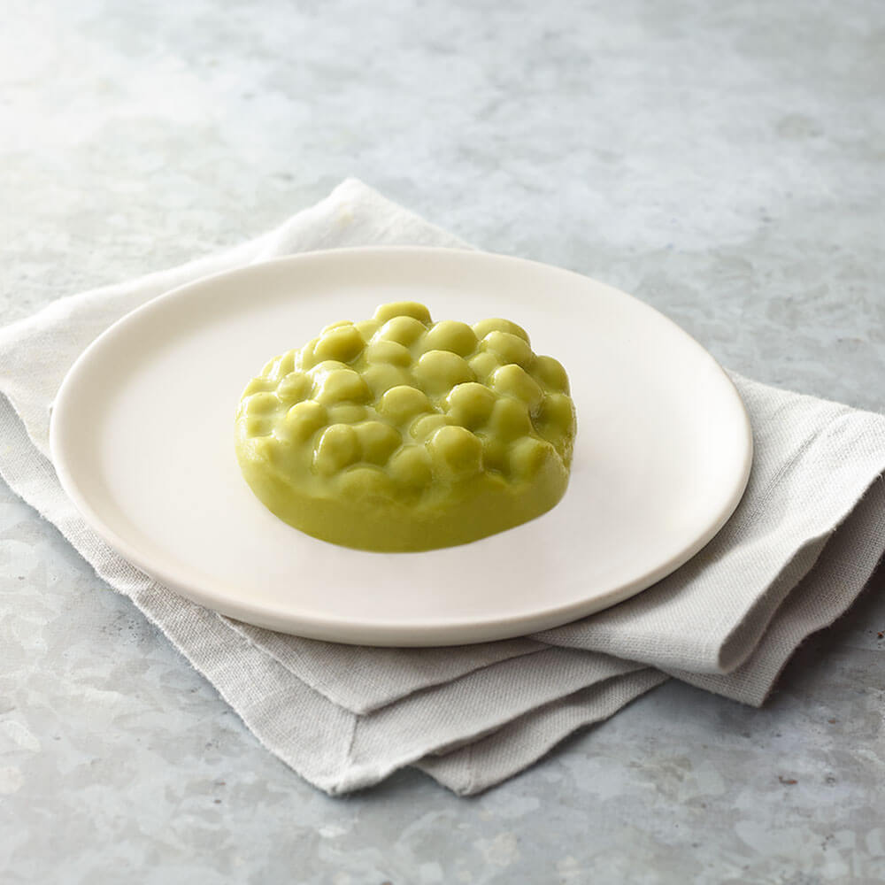 Peas on a white plate with a light gray background.