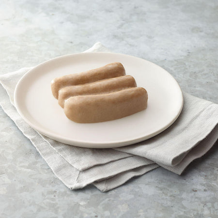 Three hot dogs on a white plate with a light gray napkin underneath, on a light gray surface.